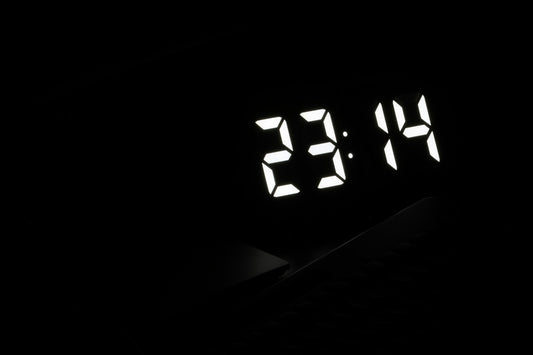 Réveil numérique aux chiffres lumineux affichant l'heure dans une chambre plongée dans l'obscurité